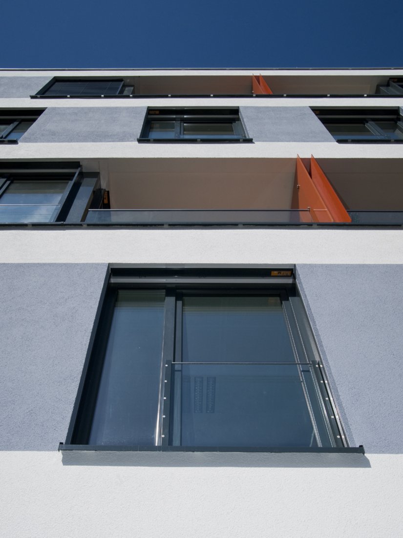 The orange red offset balcony dividing walls are the counterpart to the matt, raw render.