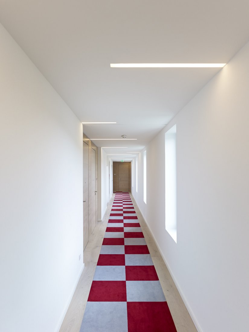 The walls in the long corridors are decorated in white. This makes the red-white on the flooring even more eye-catching.