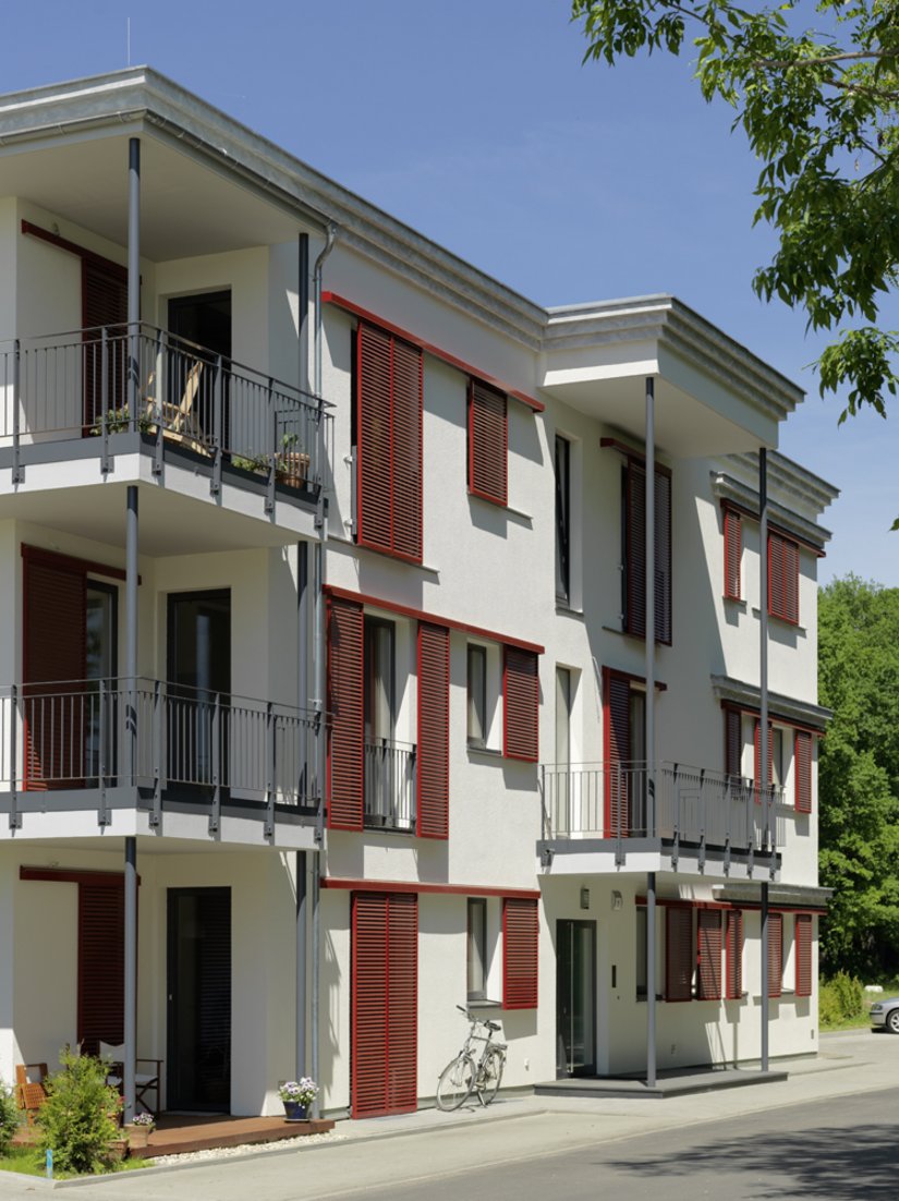 The warm broken white of the facade creates a clear contrast to the anthracite windows, doors and balcony balustrade.