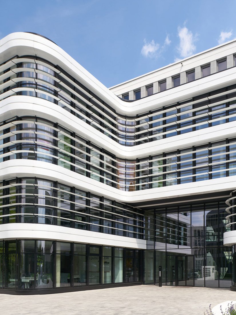 The main staircase and the generous atrium in exposed concrete are architectural highlights, along with the curved, white, post-and-beam facade with its accompanying shade and character-giving wing profiles.