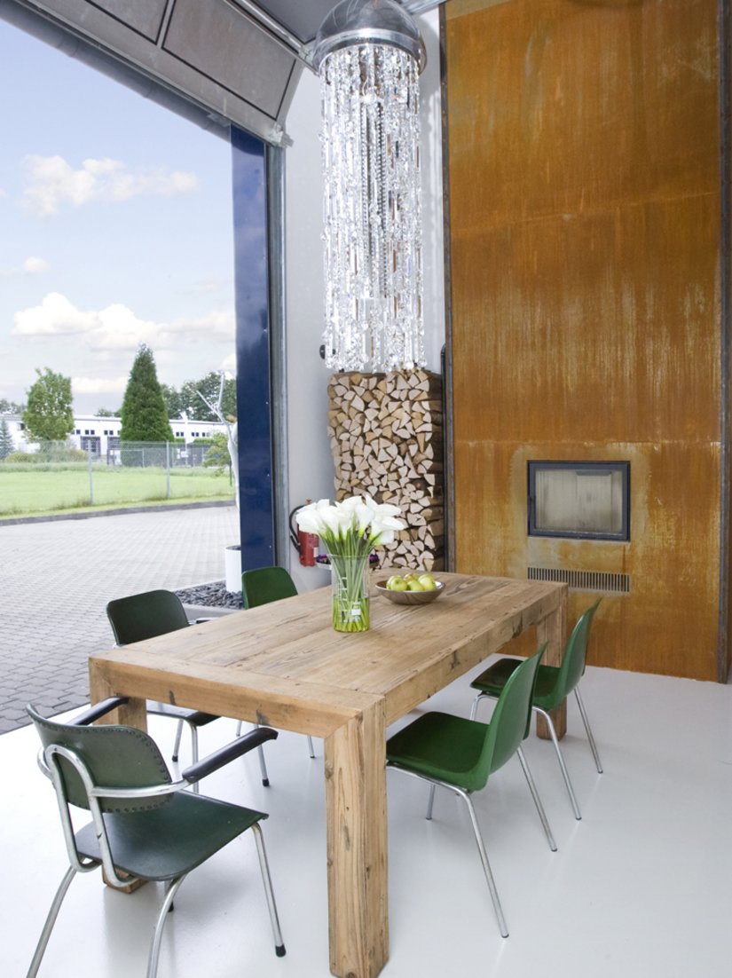 The warm wooden table, together with the fireplace inset in the wall and its rust-colored panel, mark the heart of the loft.