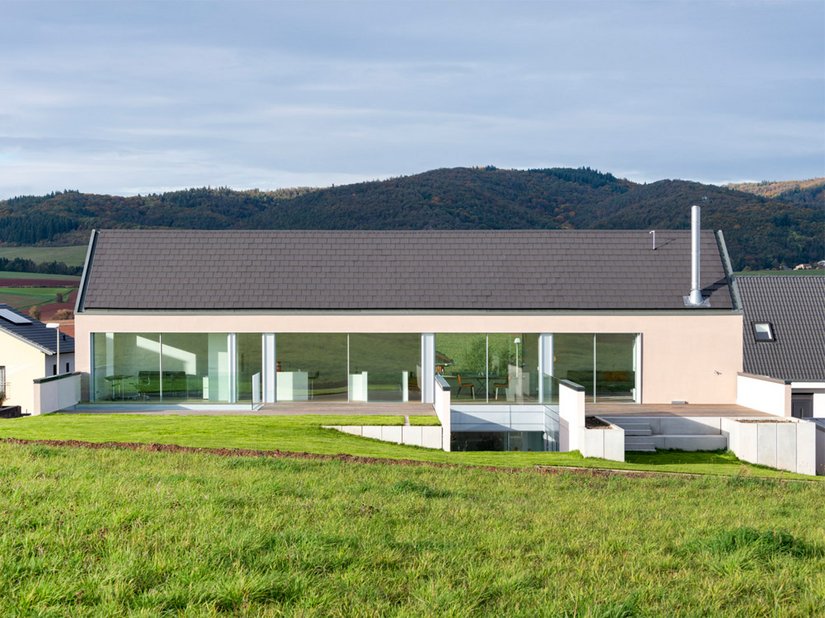 The residential home, which was completed in 2019, surprises visitors with its elegantly simple cubature, which also makes use of the natural course of the terrain.
Photo: ©Johannes Marburg, Geneva