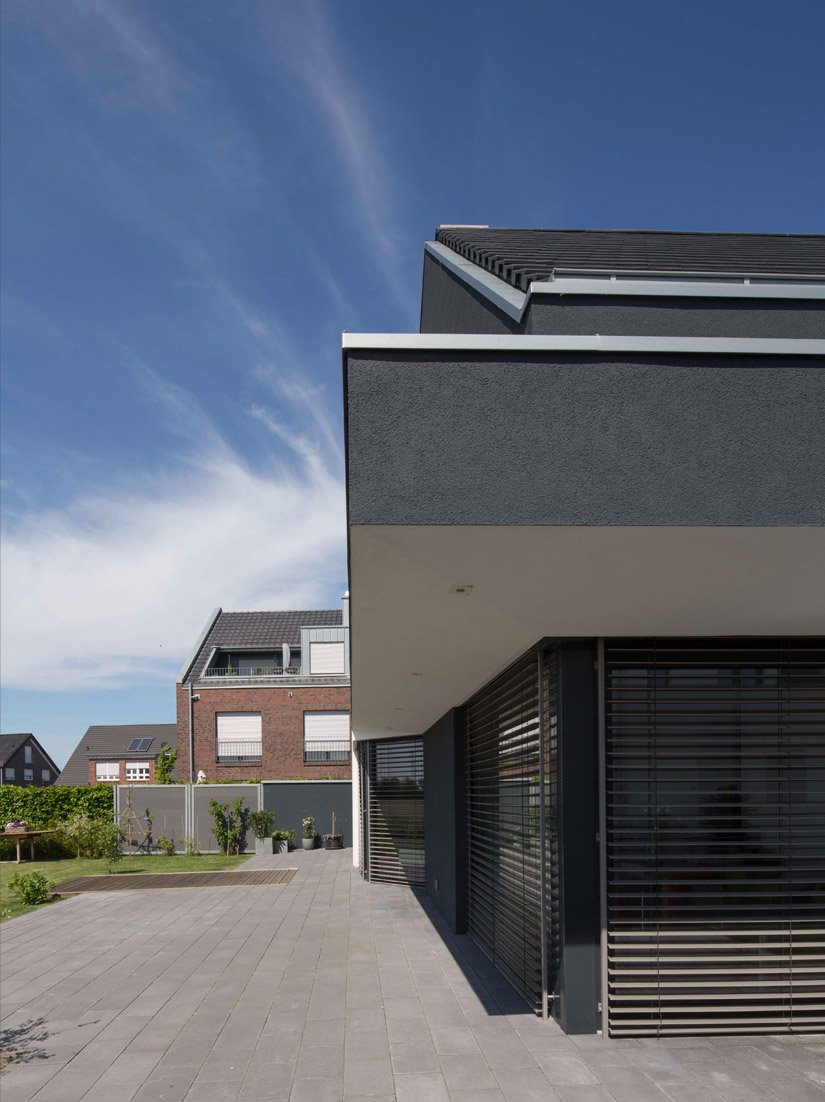 The white, beveled window and door reveals and the white side and bottom edges of all projecting and recessed structures create an exciting interplay with the anthracite colored volume of the actual house.