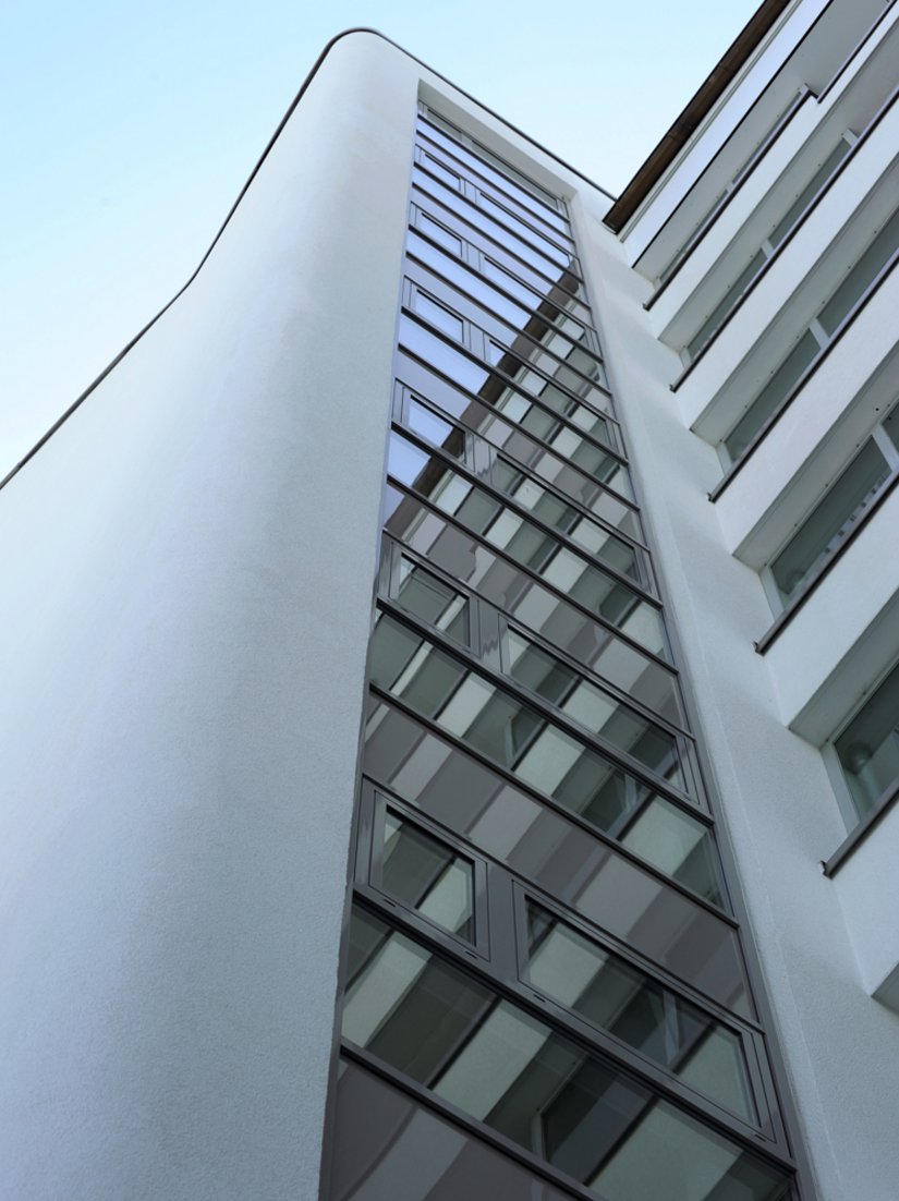 A wide window strip in the stairwell underlines the modern look of the high-rise building.