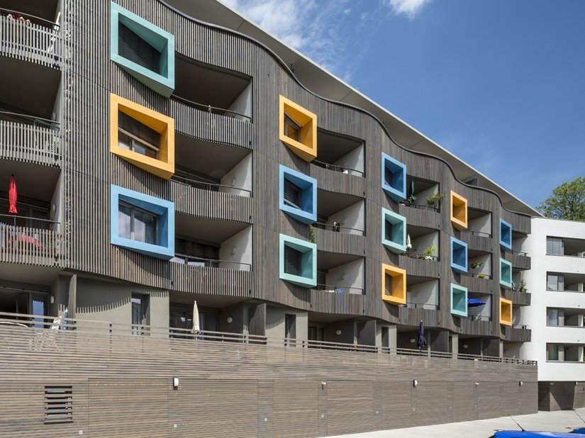 <p>Here, the facade was transformed into a waved wooden shell with integrated balconies and colored peep-boxes for the individual apartments.</p>