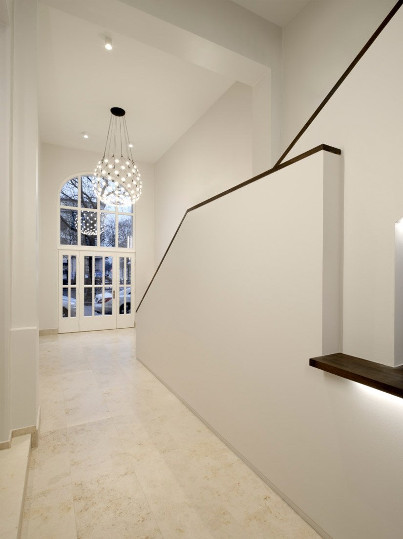 The entrance is covered in bright white, marble and smooth walls, which complement each other to create a spacious threshold.