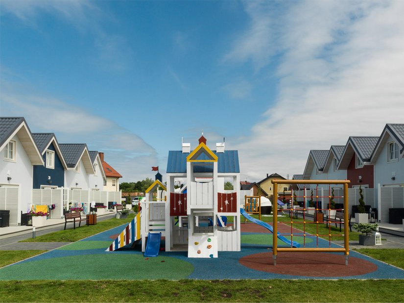 The playground provides a recreational area between the wooden houses.